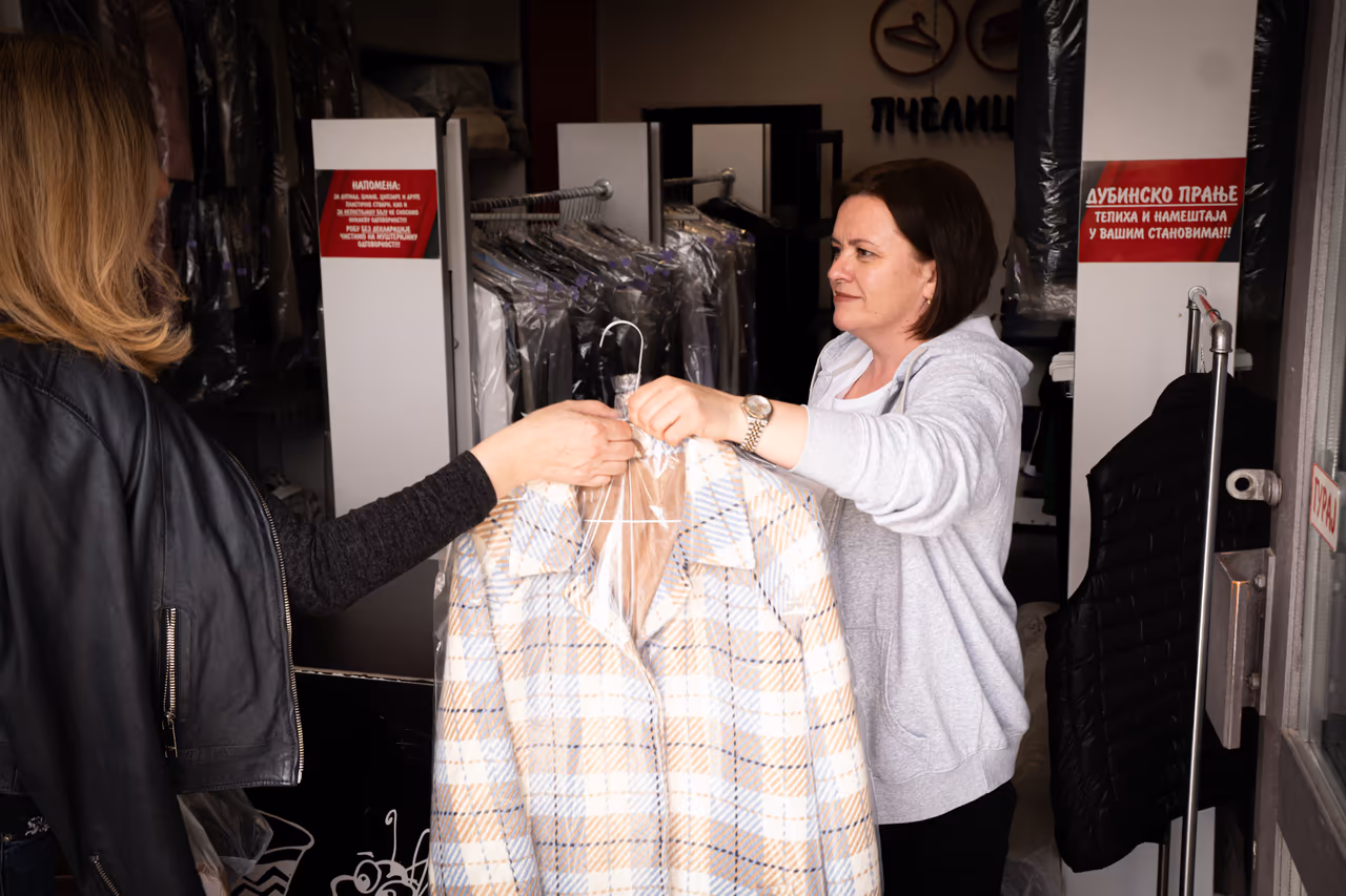 Customer receiving cleaned garment at the dry cleaning shop